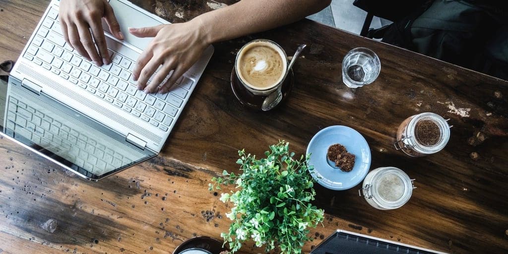 Laptops, notebooks and coffee cups on a shared work table.