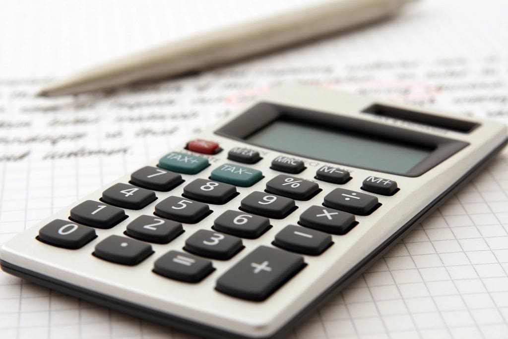 A desk calculator resting on handwritten notes.